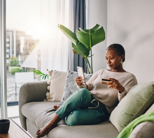 Photo of a woman sitting on the couch while using her cellphone